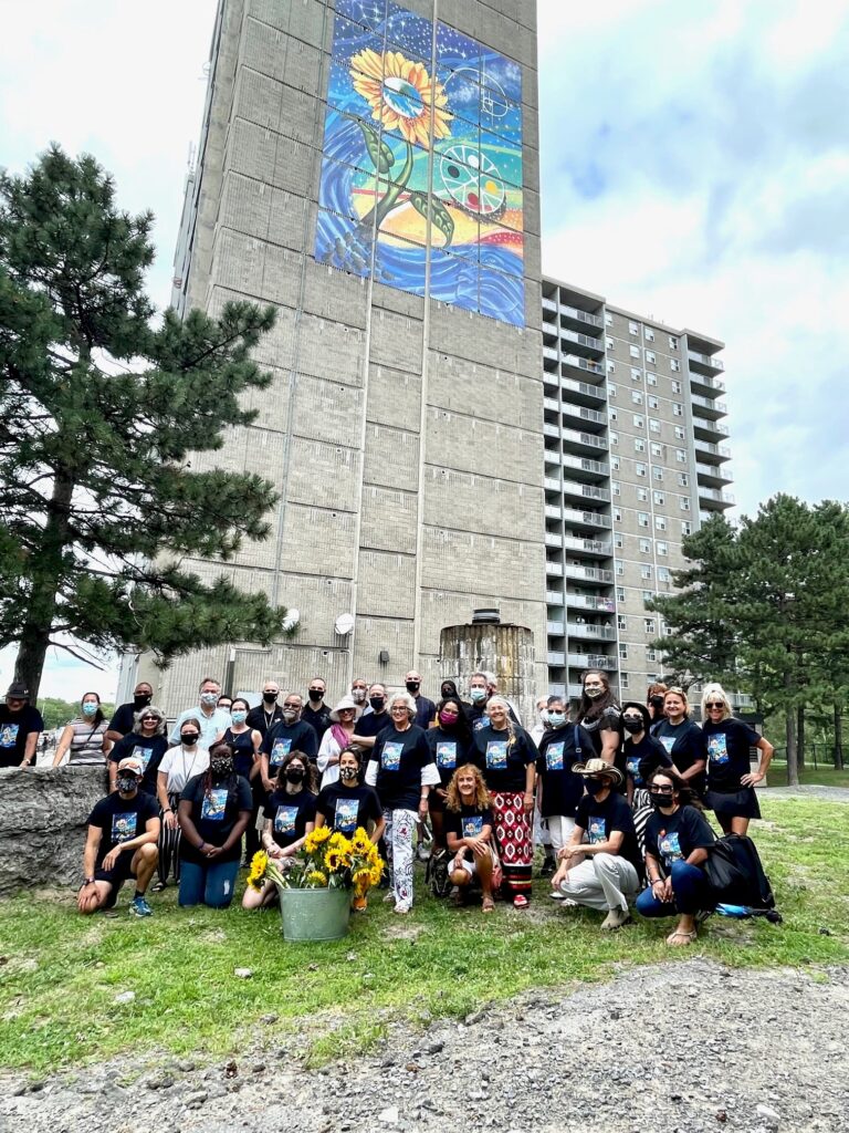 Group photo at 362 Bank, Wisdom mural in the background.
