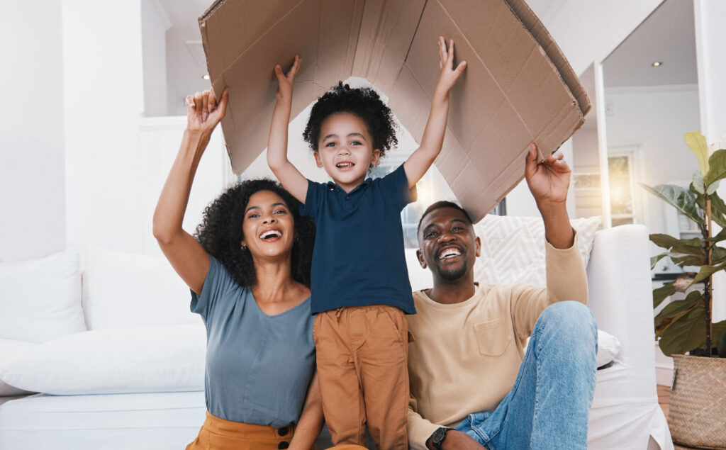 Family, roof and insurance, support and protection at home with parents, child and happy in portrait. People in living room, shelter and care with safety and love, real estate or property with box